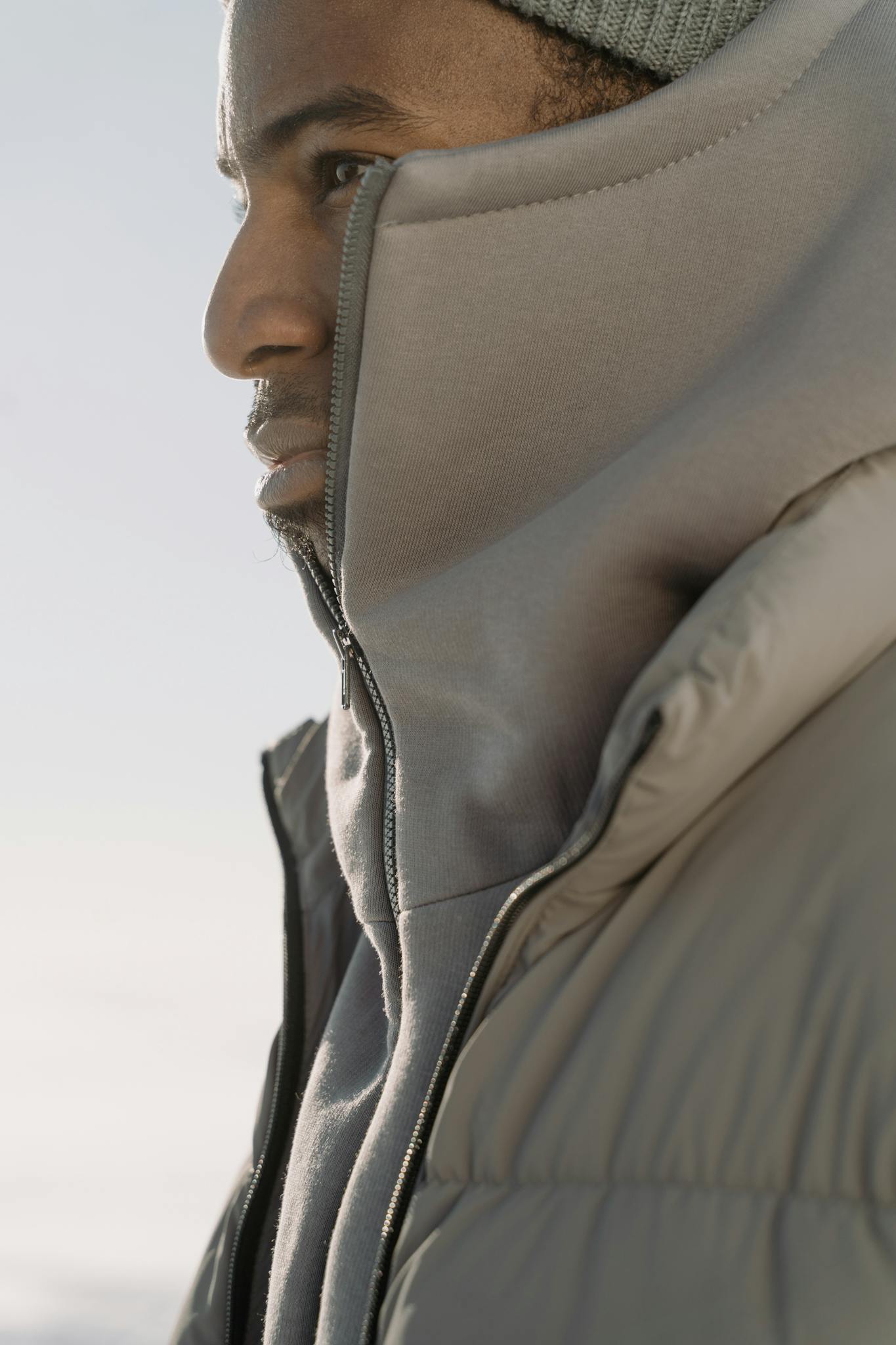 Close-up profile of a man in a hoodie and puffer jacket. Fashionable winter style.