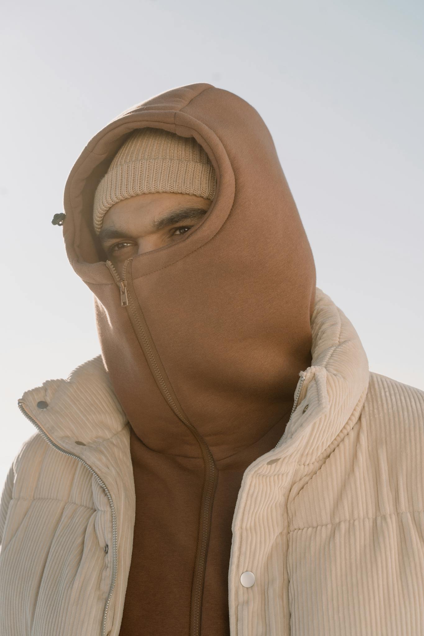 Portrait of a young man bundled up in a hoodie and puffer jacket for cold weather.